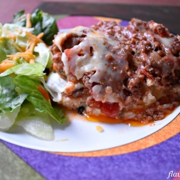 A serving of gluten free lasagna and side salad on a dinner plate.