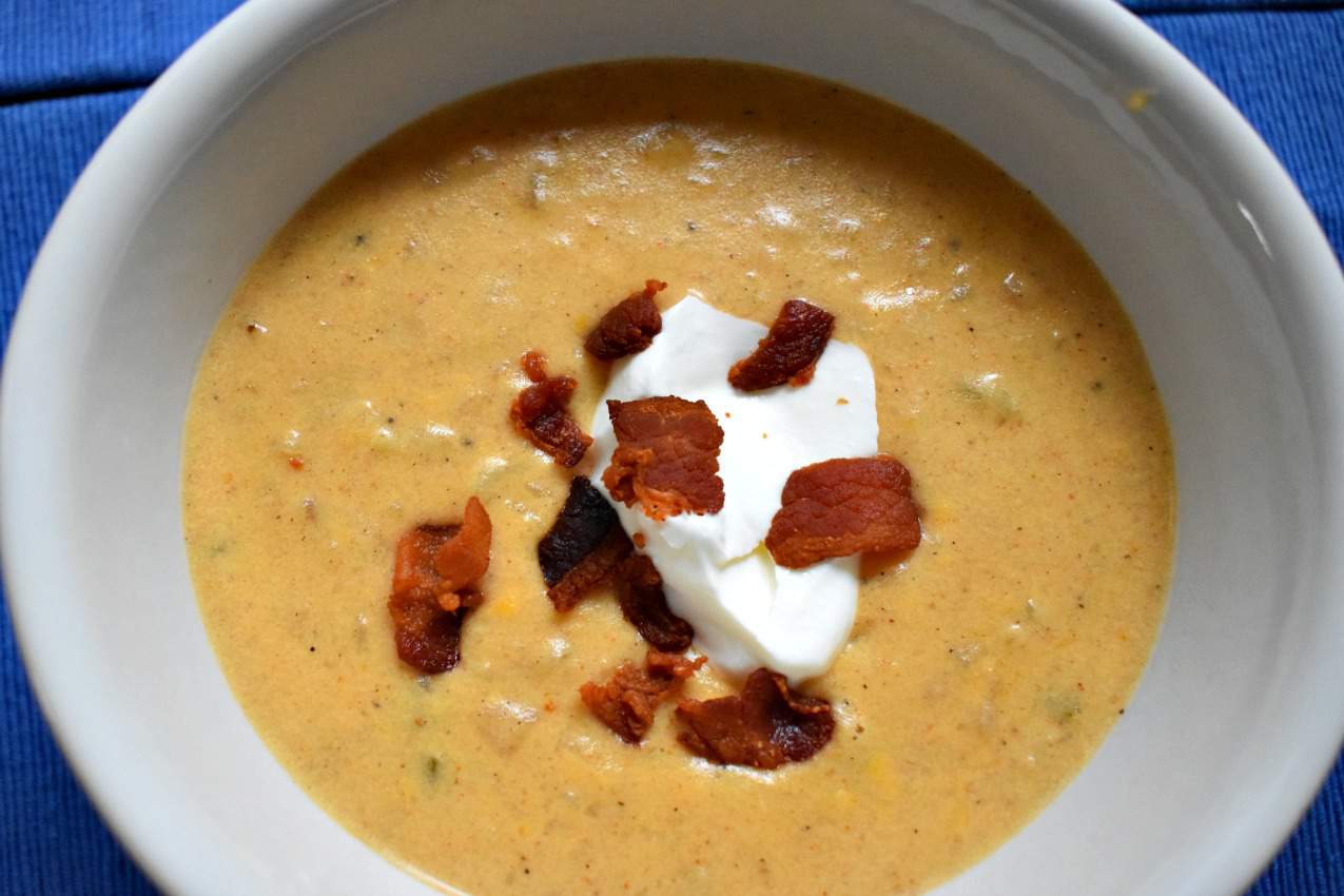 Overhead view of a white bowl filled with Creamy Cheese and Potato Soup.