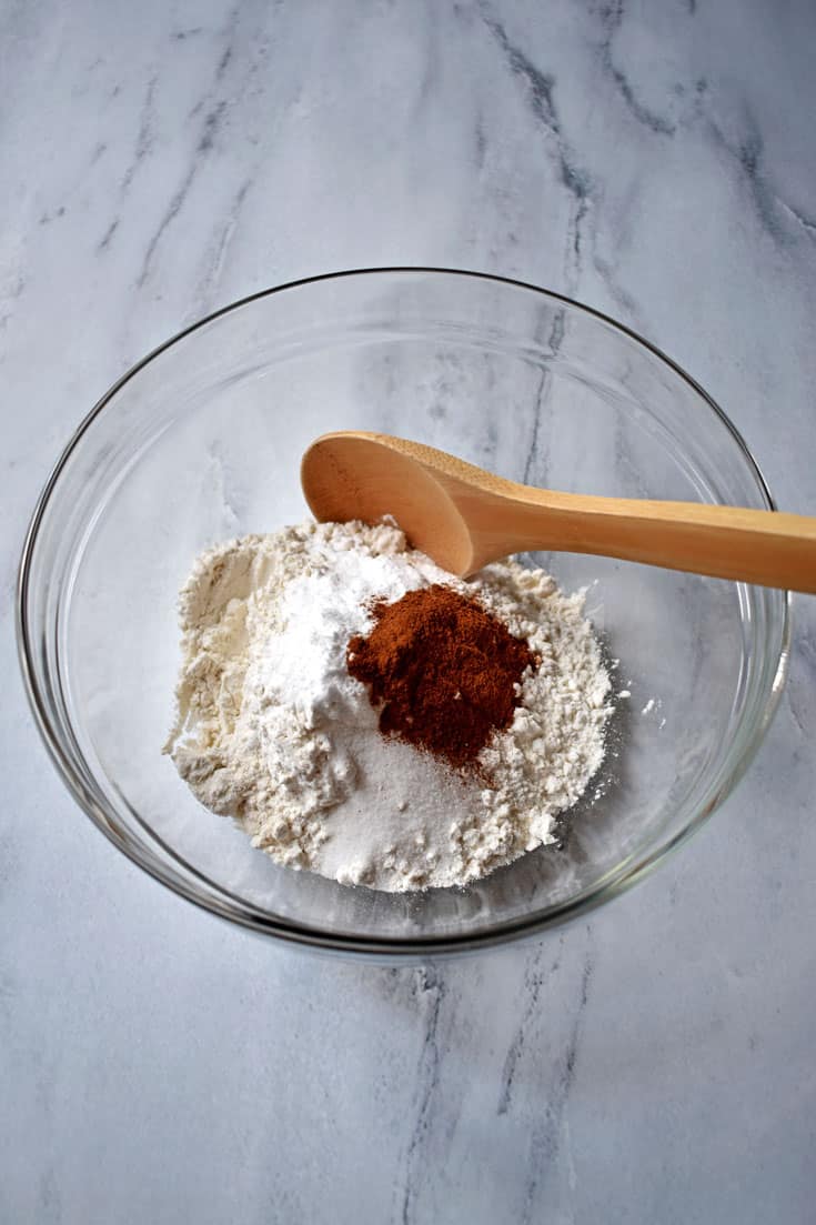 Gluten free flour, spices, and wooden spoon in small mixing bowl on granite countertop