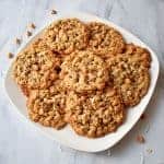 Stack of Toasted Coconut Butterscotch Oatmeal Cookies on white plate