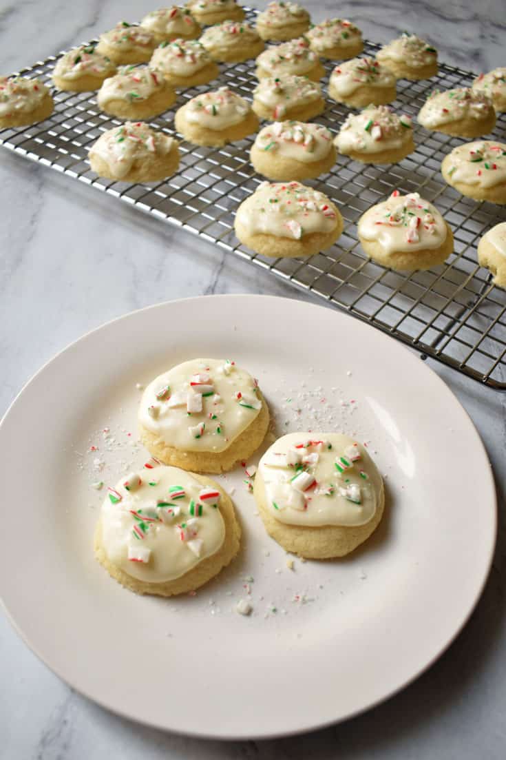 Three Gluten Free Peppermint Meltaway Cookies on white plate with more cookies on wire rack in background | Flavor Walk