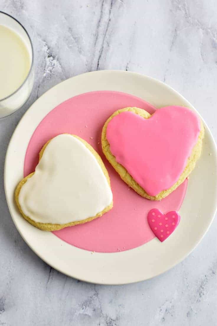 Two Frosted Powdered Sugar Cookies on a pink and white plate
