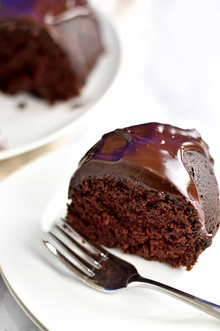 A slice of gluten free chocolate sour cream bundt cake and a fork on white plate