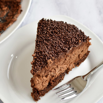 Slice of Chocolate Brownie Cheesecake {Gluten Free} and fork on white plate