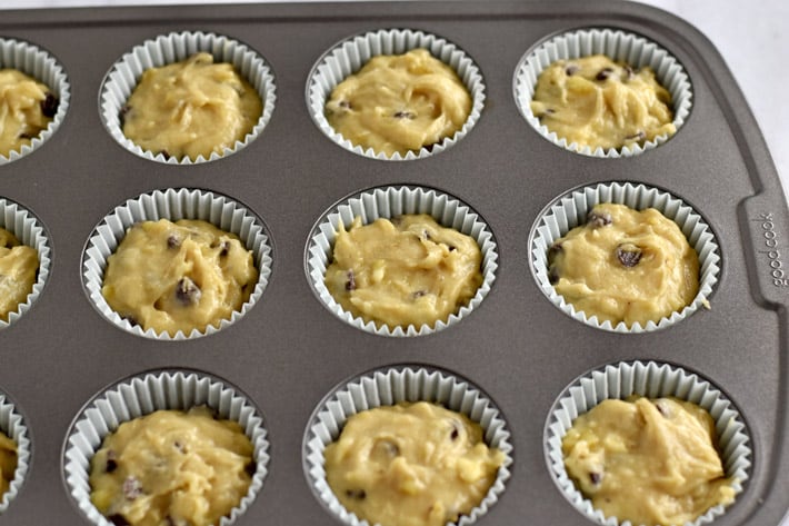 Muffin pan with paper muffin liners filled with gluten free chocolate chip banana batter