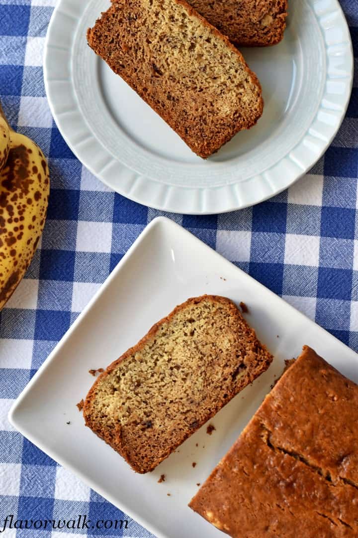 Small white plate with 2 slices of homemade banana bread in top right corner and 1 slice and remaining loaf on white rectangular plate in lower right corner