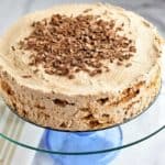 Old-Fashioned Chocolate Icebox Cake on glass cake stand with tan and white kitchen towel on the left