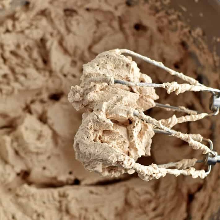 Overhead image of whipped cream on electric beaters sitting over mixing bowl of whipped cream