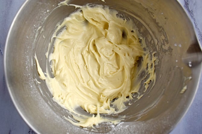 Overhead view of a silver mixing bowl with cream cheese frosting inside