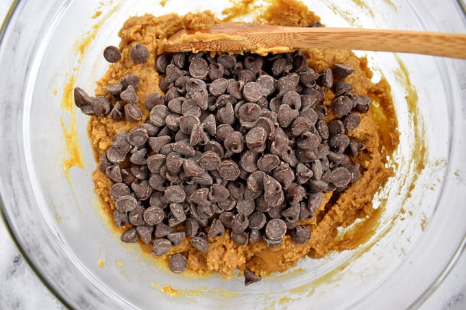 Overhead view of peanut butter cookie dough with chocolate chips and wooden spoon on top