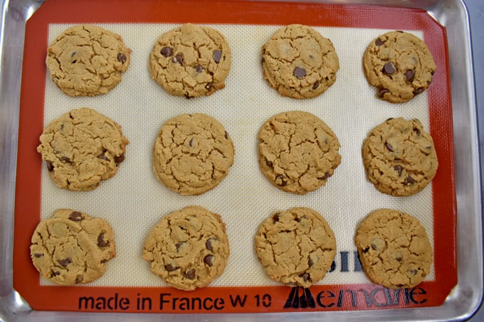 Overhead view of lined baking pan with freshly baked gluten free peanut butter chocolate chip cookies