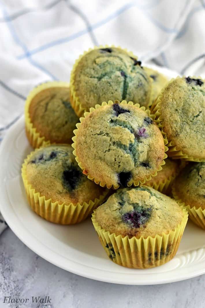 Stack of easy gluten free blueberry muffins on white plate with white striped kitchen towel in background