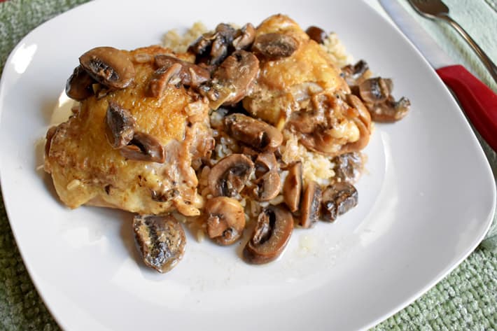 Overhead view of a serving of chicken marsala with rice on a white dinner plate