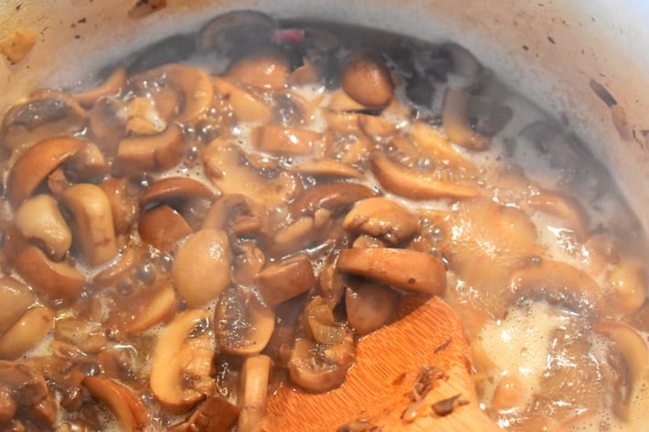 Dutch oven with mushrooms, shallots, garlic, and other ingredients for making chicken marsala
