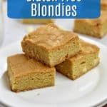 3 Gluten Free Blondies on a stack of 2 round white plates with a glass of milk and more blondies in background and blue text overlay near top