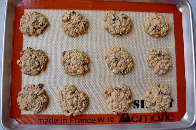 Overhead view of baked gluten free oatmeal raisin cookies on silicone lined baking pan.