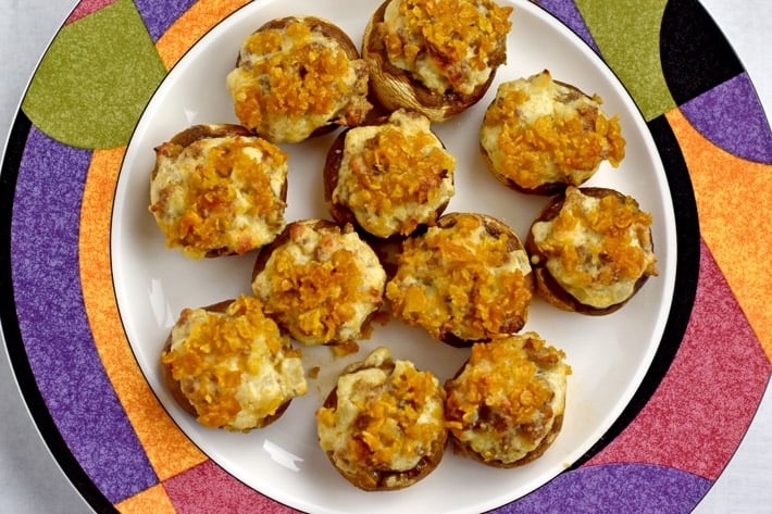 Overhead view of white plate with colorful edge filled with gluten free stuffed mushrooms.