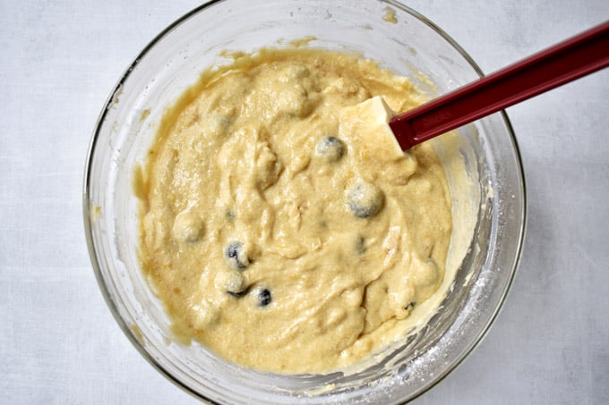 Overhead view of glass mixing bowl with gluten free banana blueberry bread batter and rubber spatula.