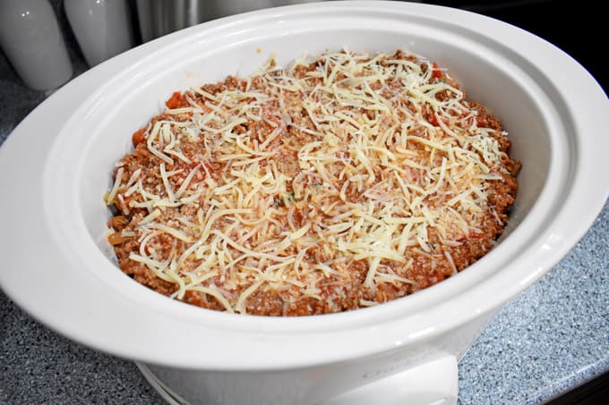 Overhead view of uncooked gluten free lasagna in a white slow cooker.