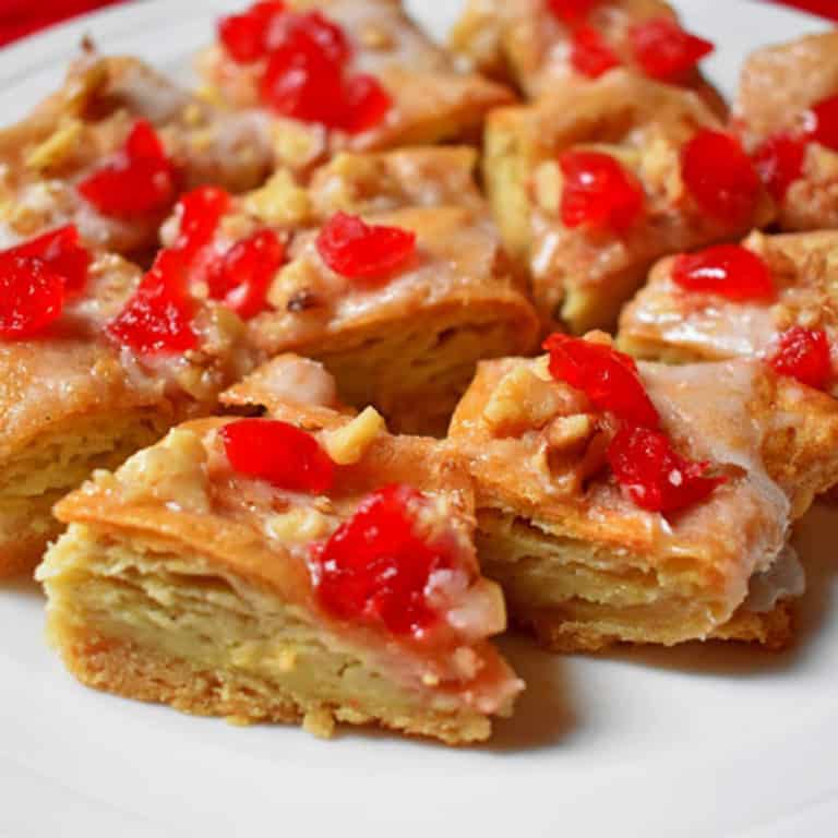 A white plate filled with pieces of maraschino decorated gluten free almond puff.