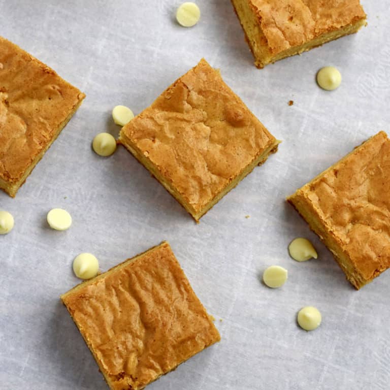 Overhead view of gluten free blondies and white chocolate chips on parchment paper.