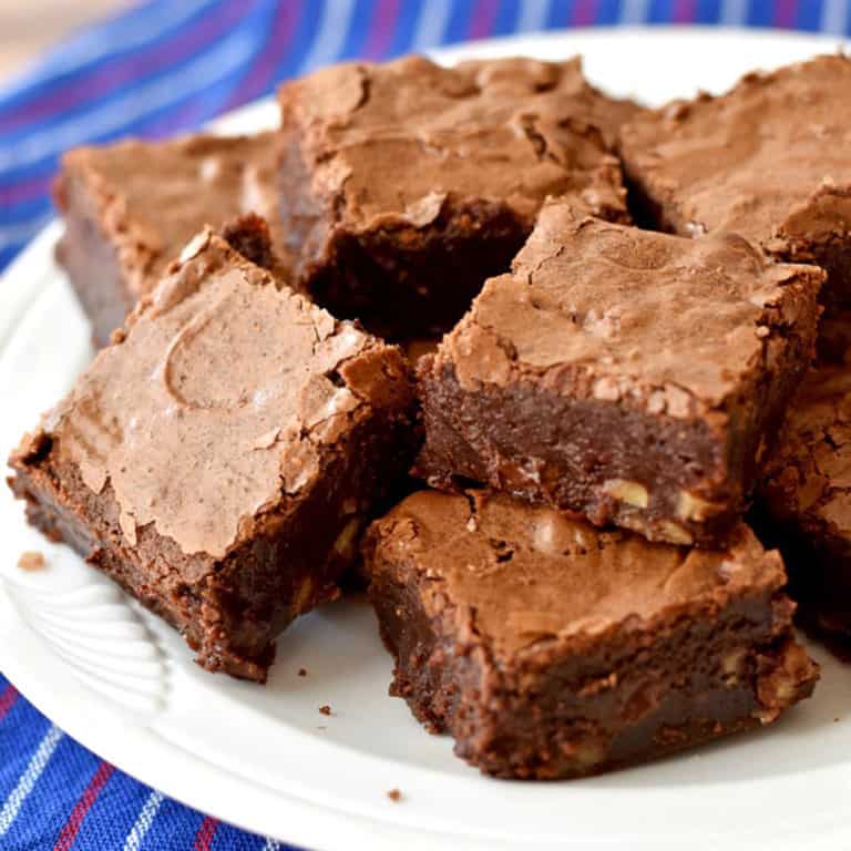 A round white plate filled with gluten free brownies sitting on a red, white, and blue striped kitchen towel.