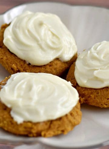 Close up view of three gluten free pumpkin cookies on a silver lined dessert plate.
