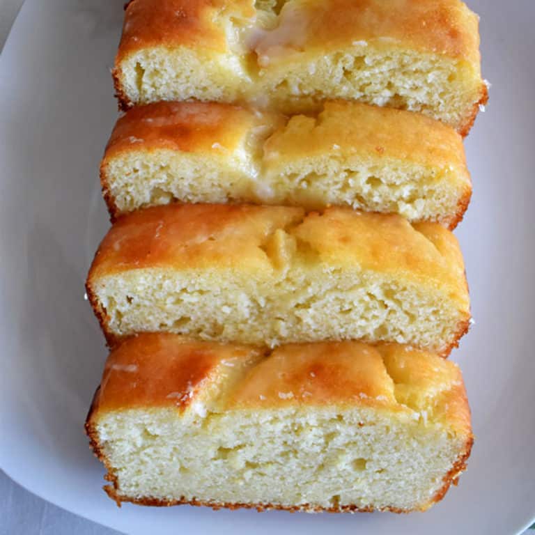 Overhead view of 4 slices of lemon loaf cake on a white plate.