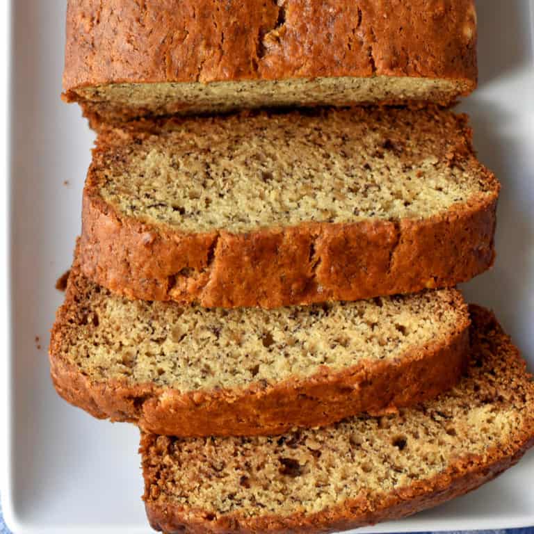 Overhead view of slices of homemade banana bread on a white plate.