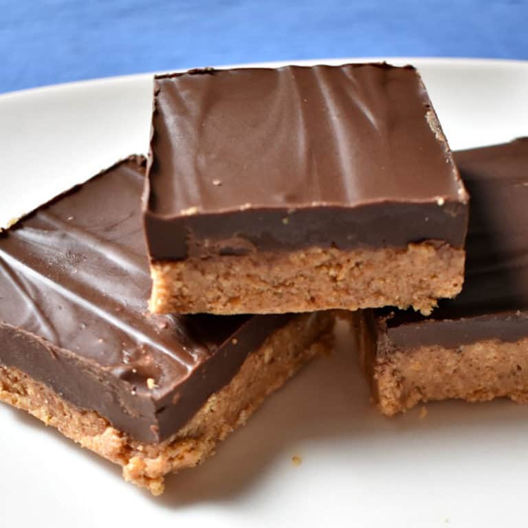 Three no bake nut butter pretzel squares stacked on a white plate.