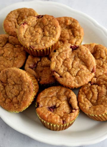 Overhead view of quinoa muffins piled on top of an oval white serving platter.