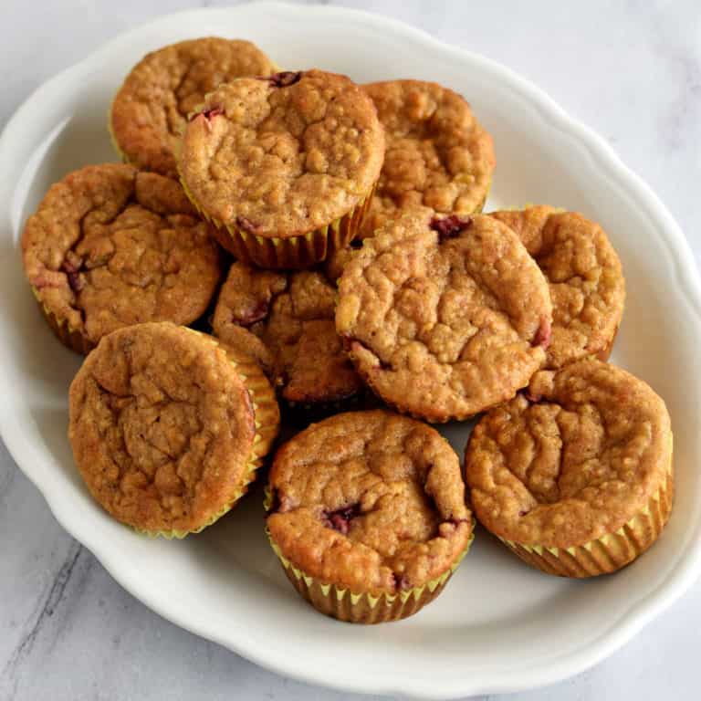 Overhead view of quinoa muffins piled on top of an oval white serving platter.