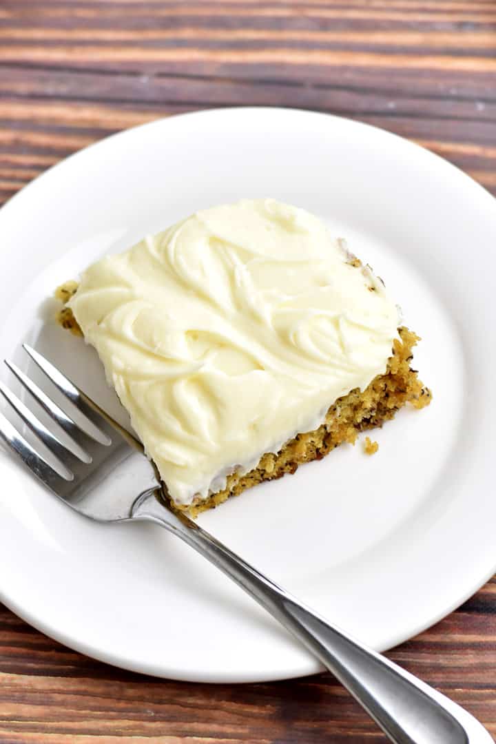 Overhead view of a slice of gluten free banana cake and a fork on a small white plate.