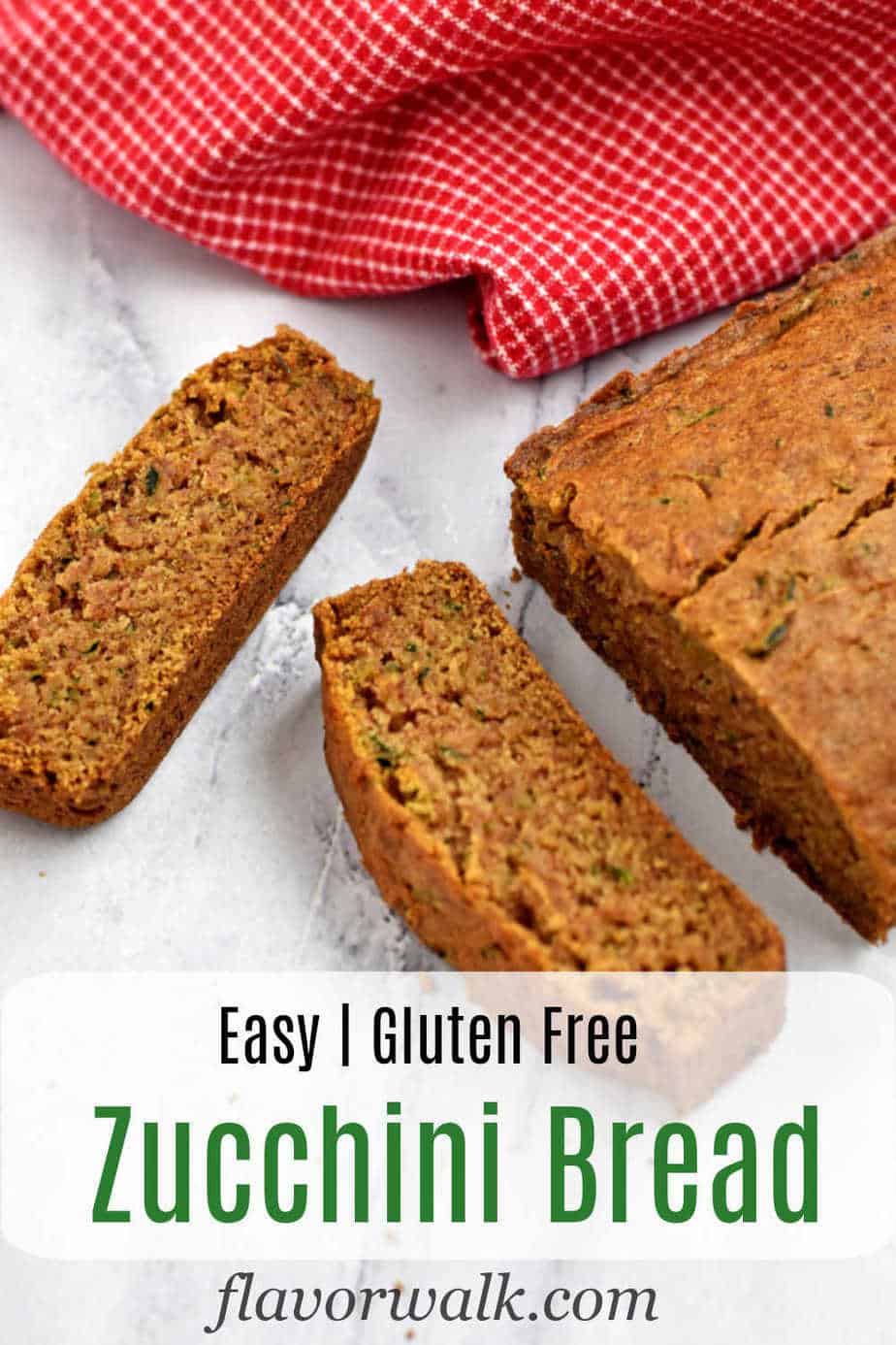 Two slices of gluten free zucchini bread on the kitchen counter, remaining loaf and a red and white checked kitchen towel in the background, and black and green text overlay at the bottom.