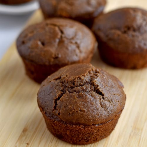 Close-up view of gluten free double chocolate muffins on a wood cutting board.