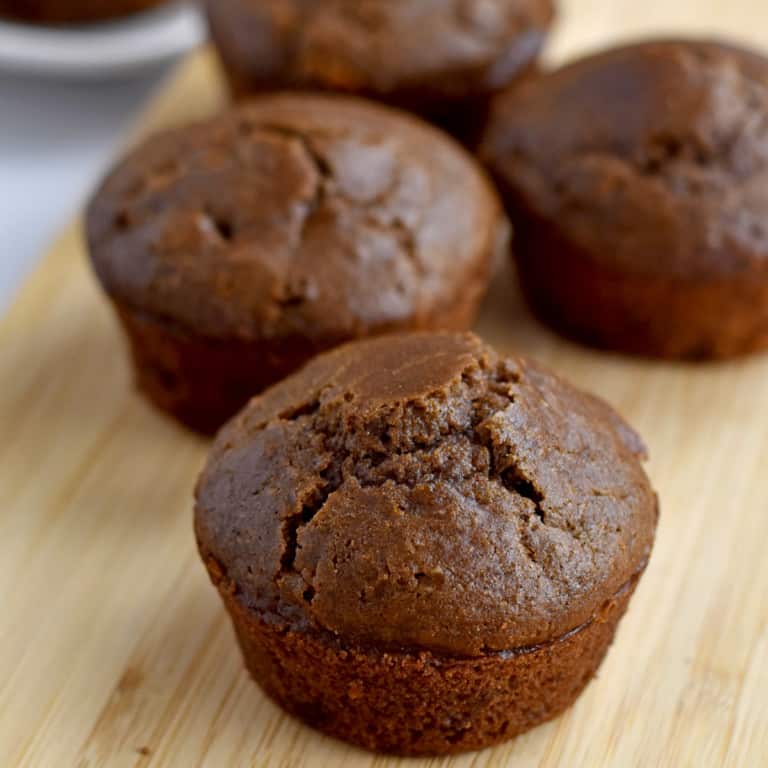 Close-up view of gluten free double chocolate muffins on a wood cutting board.