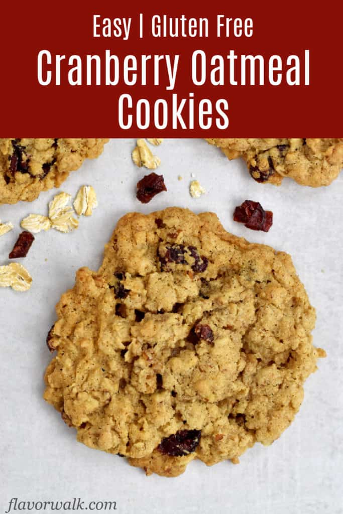 Overhead view of a gluten free cranberry oatmeal cookie with oats and dried cranberries scattered around and a red text box at the top.