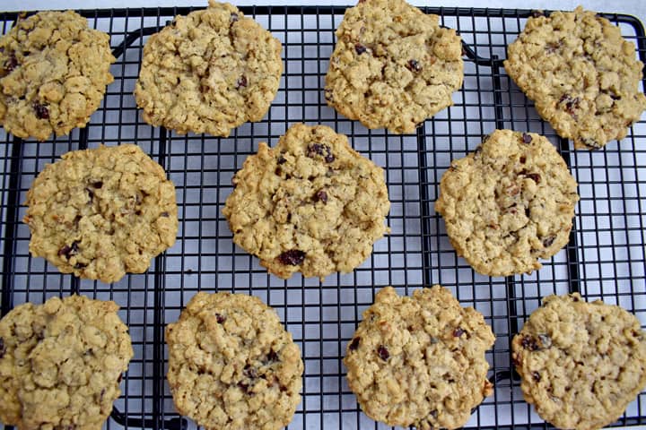 Overhead view of baked gluten free cranberry oatmeal cookies cooling on a black wire rack.