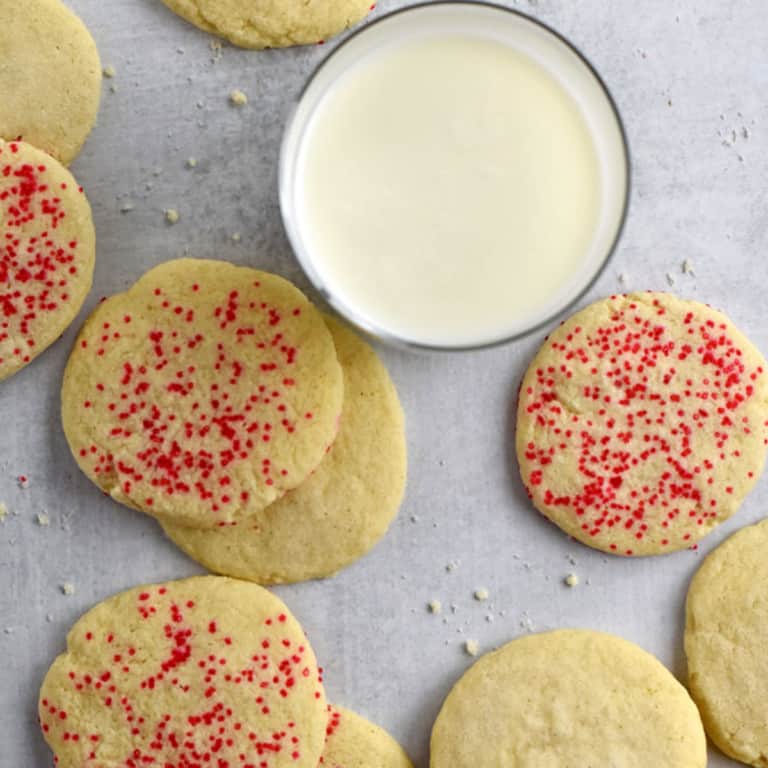Overhead view of gluten free butter cookies scattered around a glass of milk.