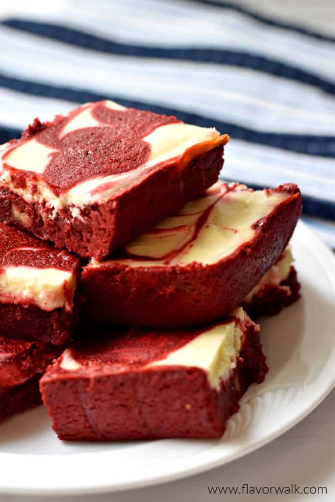 Close-up view of gluten free red velvet brownies on round white plate with a blue and white striped kitchen towel in the background.