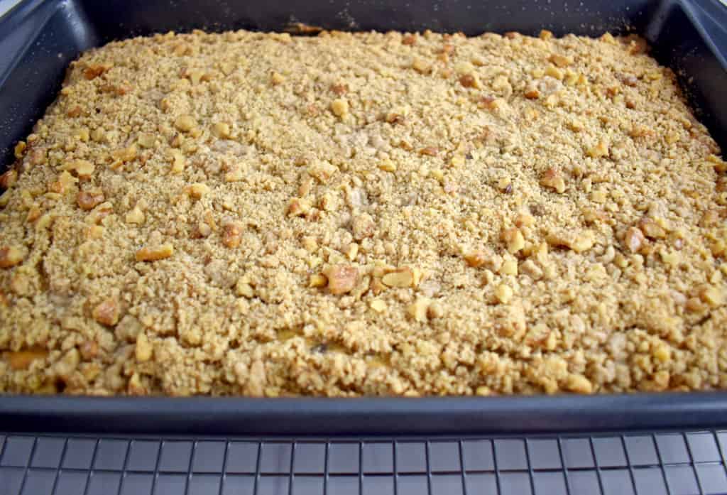 Close up view of baked gluten free crumb cake in baking pan cooling on wire rack.