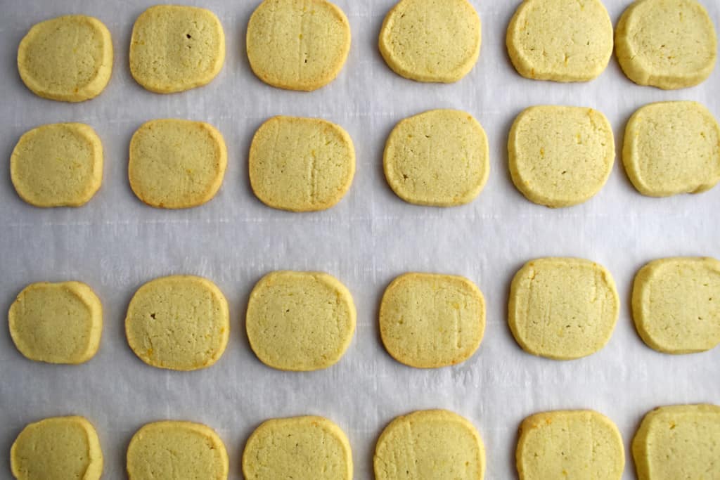 Overhead view of a parchment lined baking pan with baked gluten free lemon cookies.