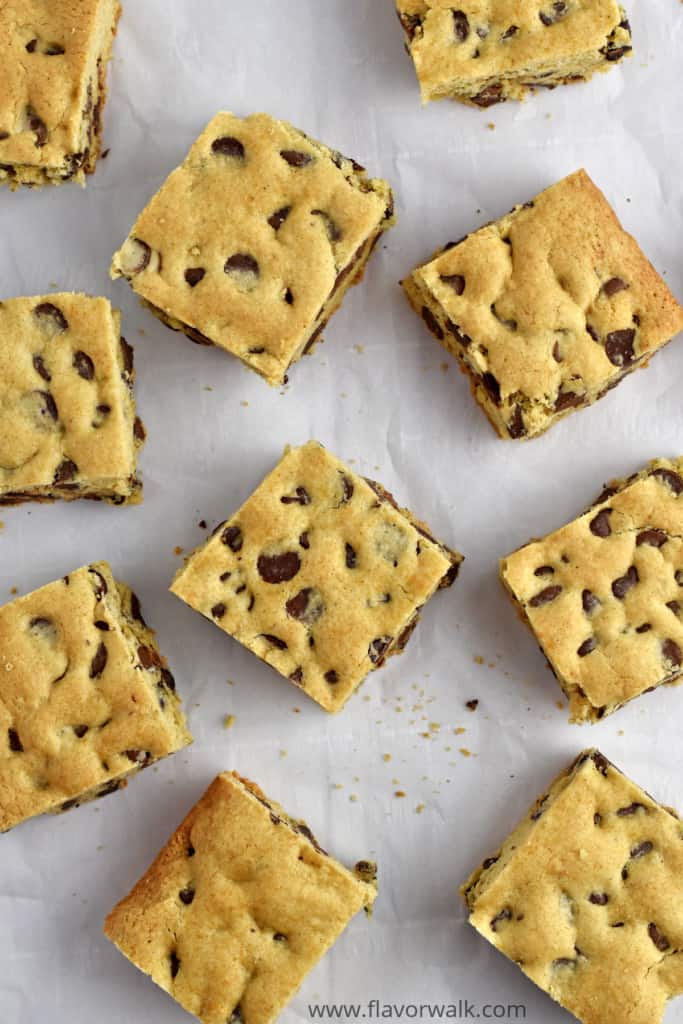 Overhead view of chocolate chip cookie bars scattered on parchment paper.