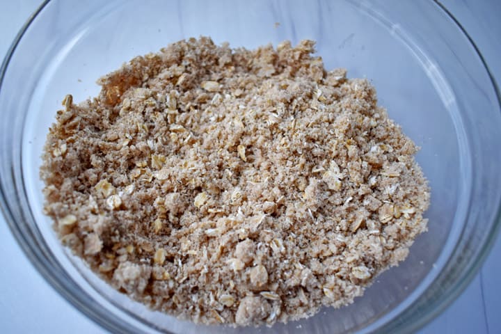 Overhead view of glass mixing bowl filled with crumb topping mixture.