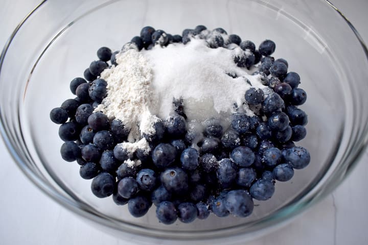 Overhead view of ingredients for making blueberry filling in a glass mixing bowl.