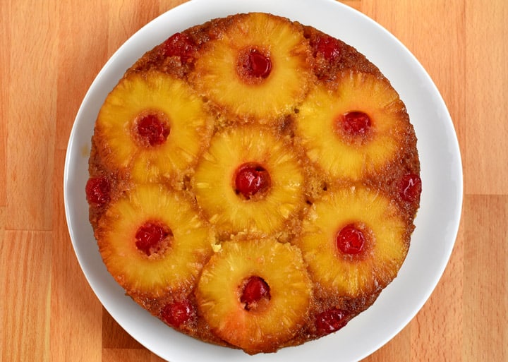Overhead view of freshly baked gf pineapple upside-down cake on round white plate.