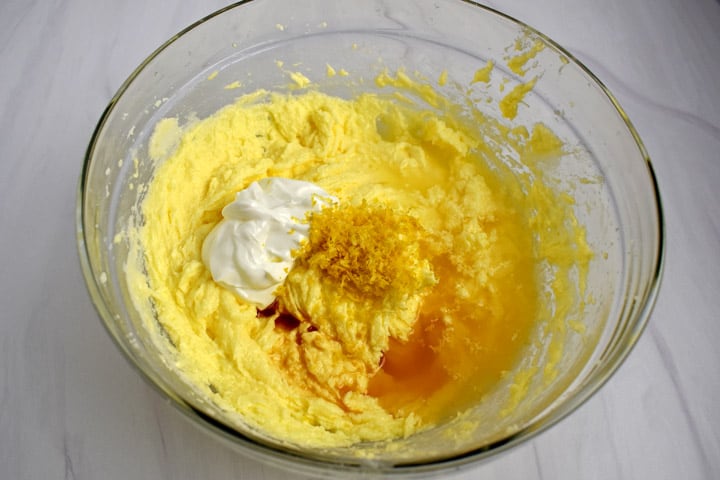 Overhead view of large glass mixing bowl with unmixed wet ingredients for making gluten free lemon pound cake.