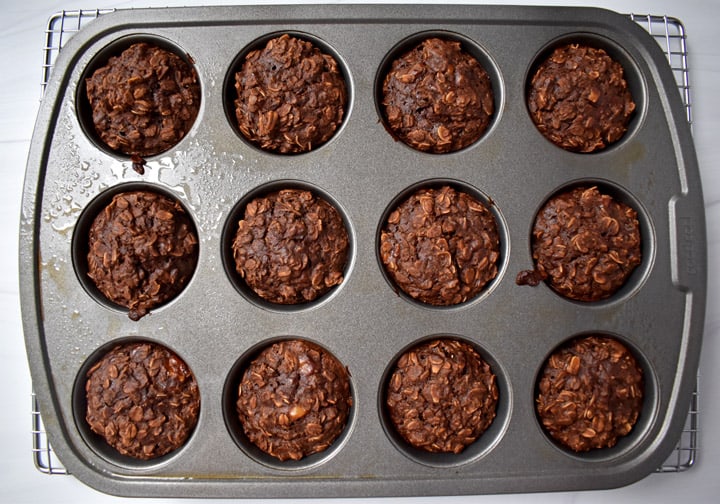Overhead view of baked chocolate peanut butter oatmeal cups in metal muffin pan.