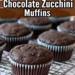 Close up view of gluten free chocolate zucchini muffins on a wire rack on top of a purple and white striped kitchen towel with brown and white text overlays near the top for Pinterest.