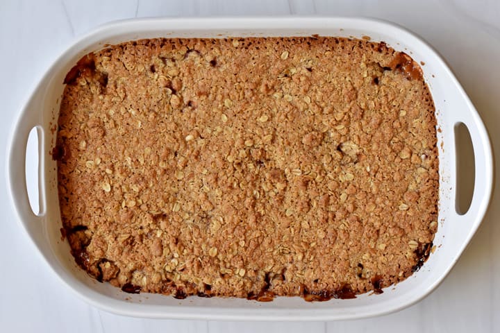 Overhead view of baked rhubarb crumble in a white 9x13-inch baking pan on counter.
